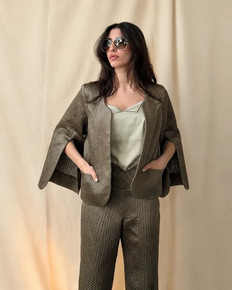 Closer view of the Sedar Jacket and Trousers, emphasizing the lustrous embossed fabric texture, open sleeves, light-toned top, and soft neckline