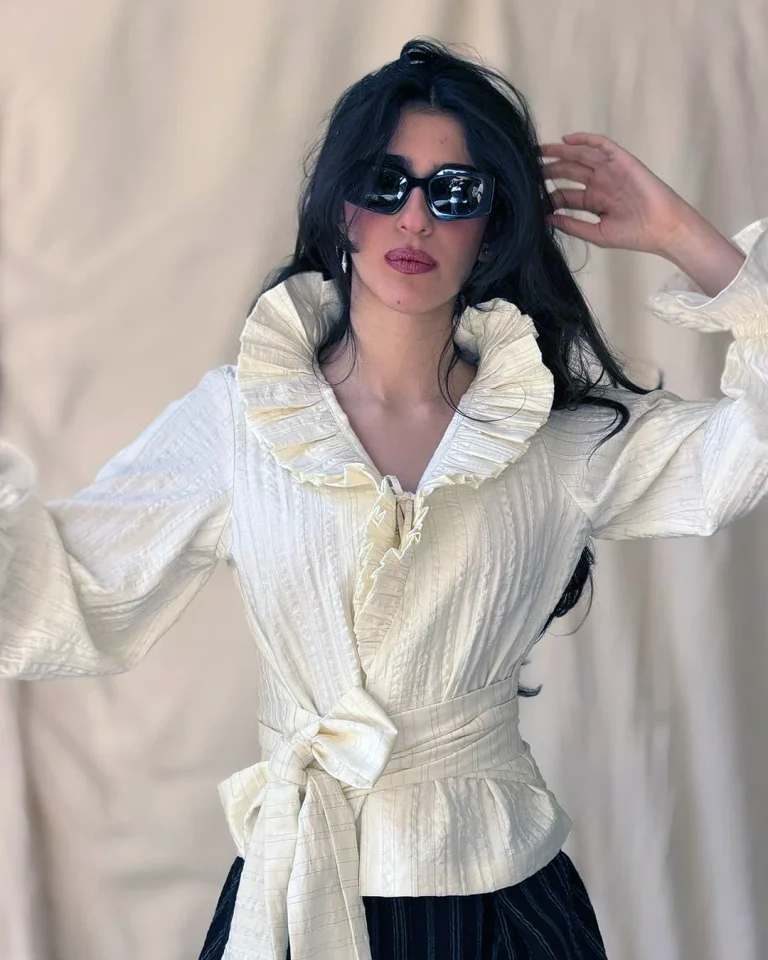 Half-body view of the Queen taffeta blouse with a ruffled collar, wrapped front, and long fabric sash
