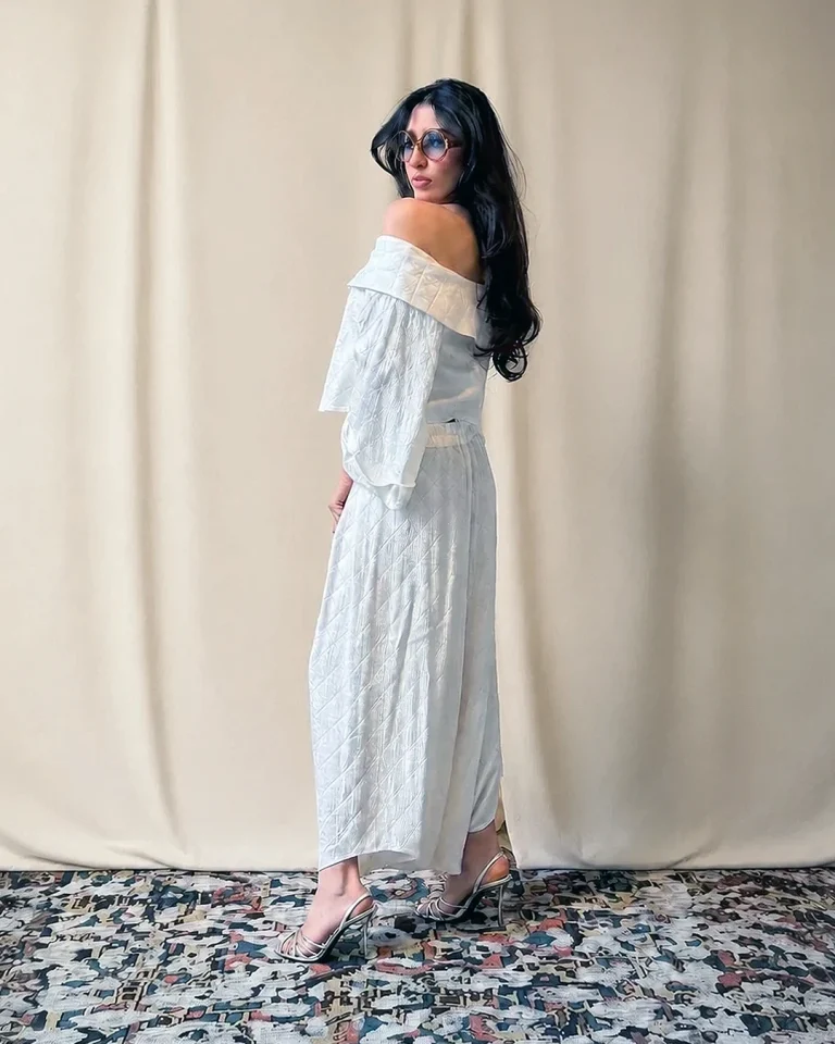 Three-quarter back view of the Sepid look with an off-shoulder blouse, relaxed sleeves, and long embossed silk culottes