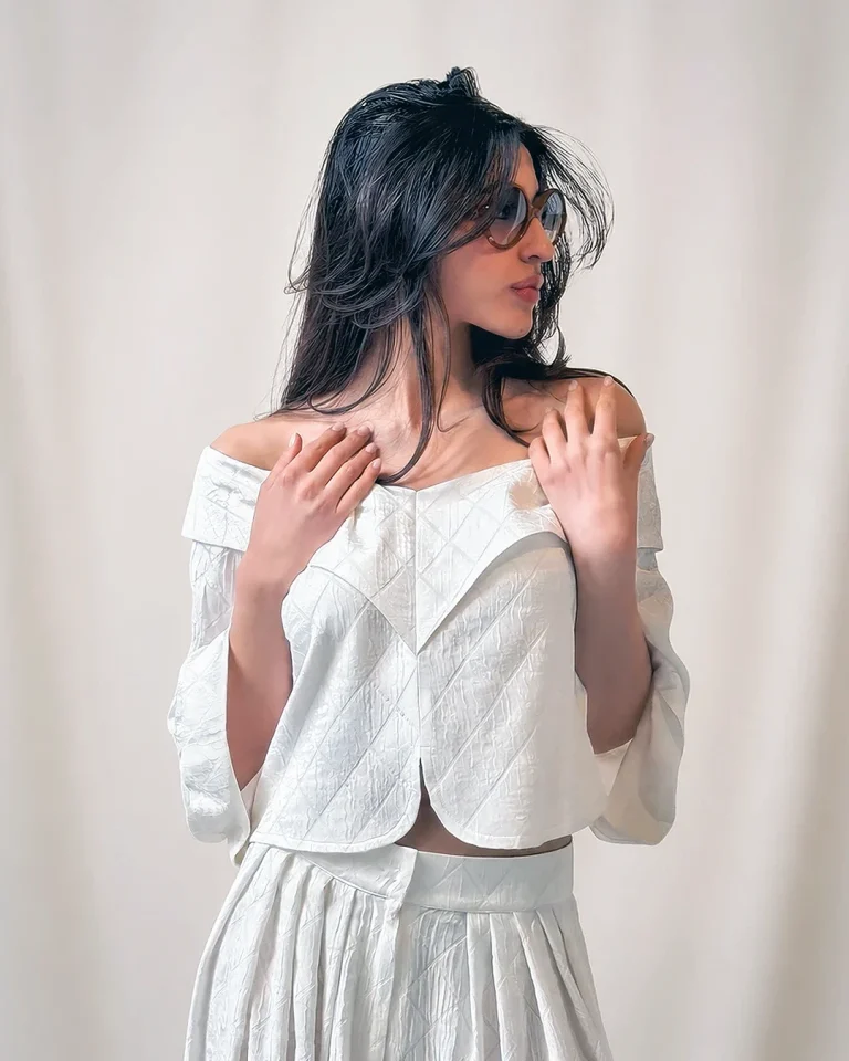 Close-up view of the Sepid off-shoulder blouse showing the embossed geometric silk texture and pleated culottes