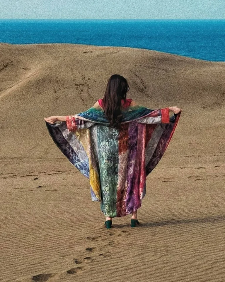 Back view of the Atlas Daraei Aba outdoors with the garment fully opened in motion over sand