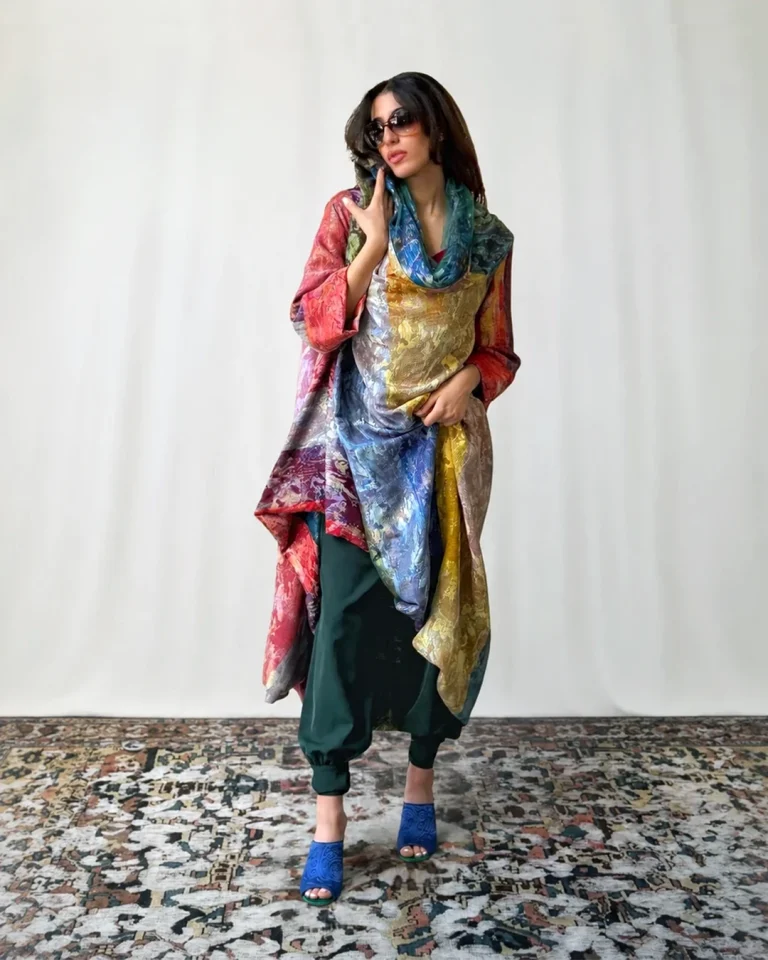 Front view of the Atlas Daraei Aba with layered blue, green, gold, and burgundy tones over dark trousers