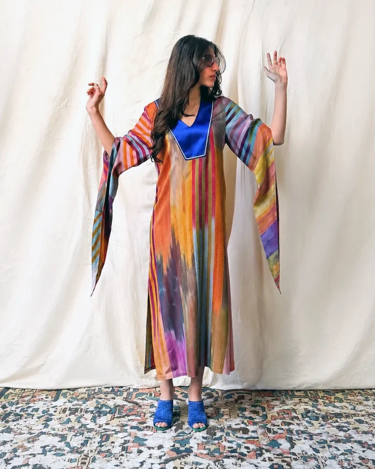 Full-length studio view of Look 15 from the Cusp collection, featuring the colorful Darayi Silk Kaftan with a glossy blue neckline, flowing sleeves, and blue shoes.