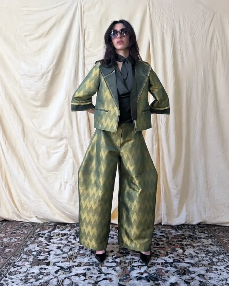 Look 18 Zarrin styled with wide green and gold trousers, a tie-neck blouse, and a matching jacket from the Cusp Spring/Summer 2026 collection
