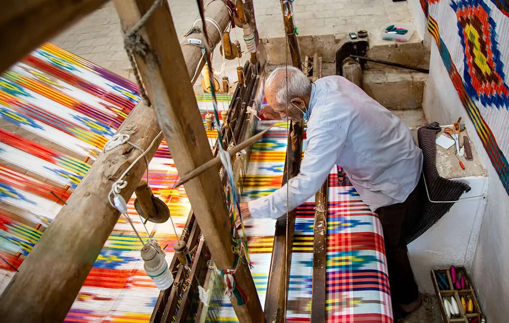 A weaver working at a traditional wooden loom, part of Yazd's daraayi ikat weaving tradition